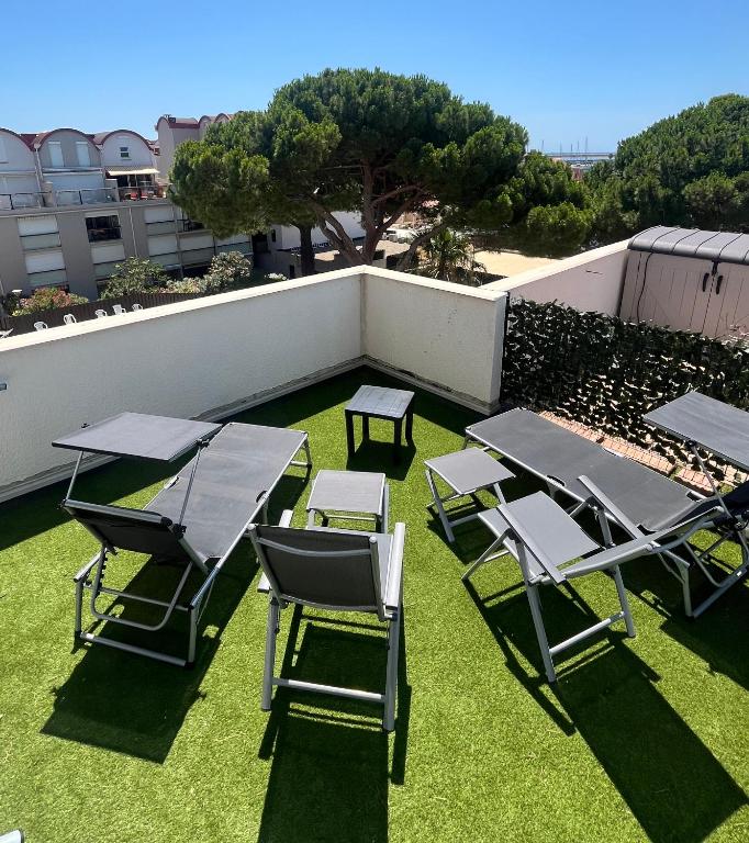 un groupe de tables de pique-nique et de chaises sur l'herbe dans l'établissement L'appart D79, à Gruissan