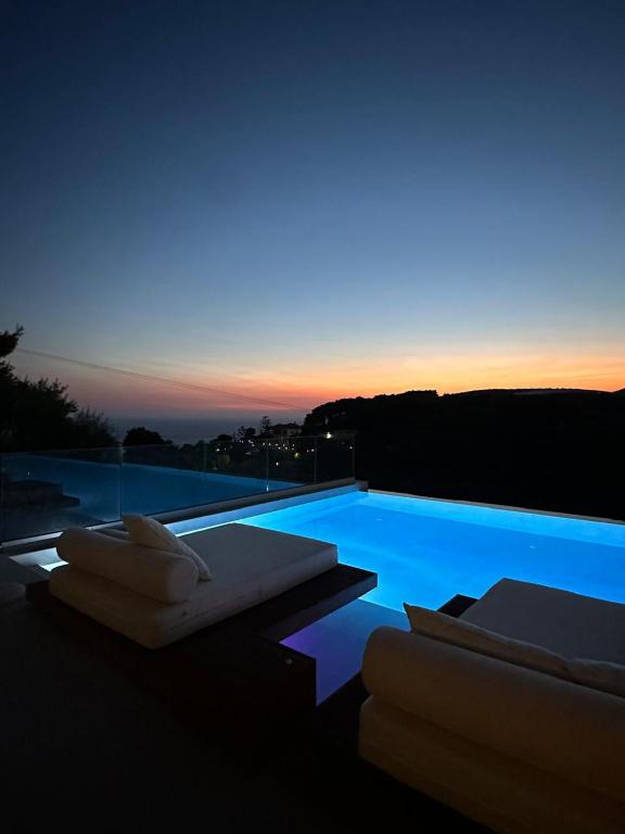 a swimming pool with two lounge chairs and a sunset at Myzith Luxury Suites in Keri