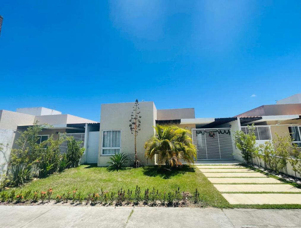 a house with a palm tree in front of it at Casa com Piscina em Condomínio Fechado na Praia do Francês in Marechal Deodoro