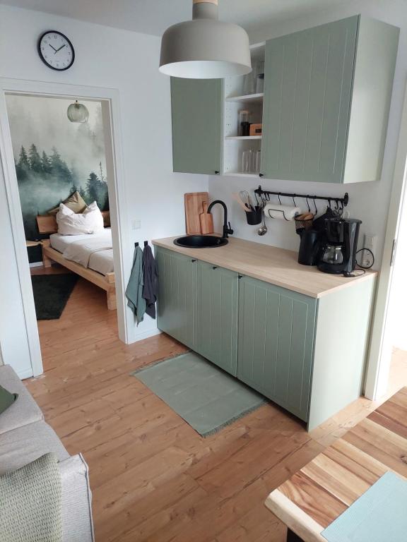 a kitchen with green cabinets and a room with a bed at Ferienwohnung Schwingestraße in Dinghorn