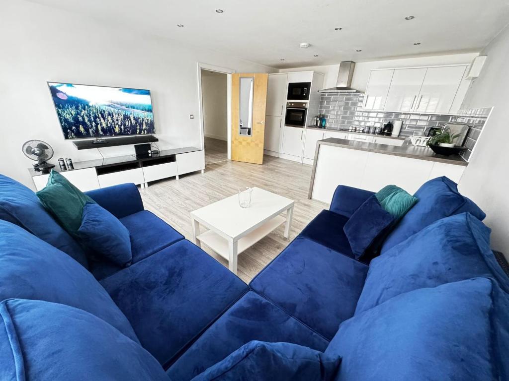 a blue couch in a living room with a kitchen at RNM - Business Professionals Stay, Walsall City Centre, 2 Bedroom with ensuite and bathroom, Entire Place, Kitchen & Washroom with amenities, Smart Tv, Easy Access, Fast WiFi, Parking Nearby, Great transport links in Walsall