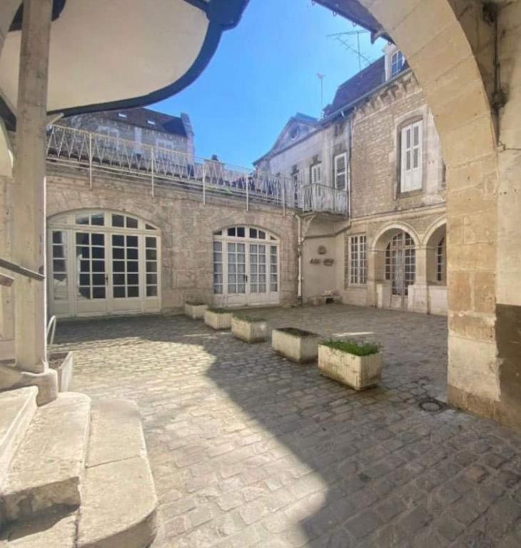 un grand bâtiment en briques avec une cour en face dans l'établissement La maison papillon, à Tonnerre