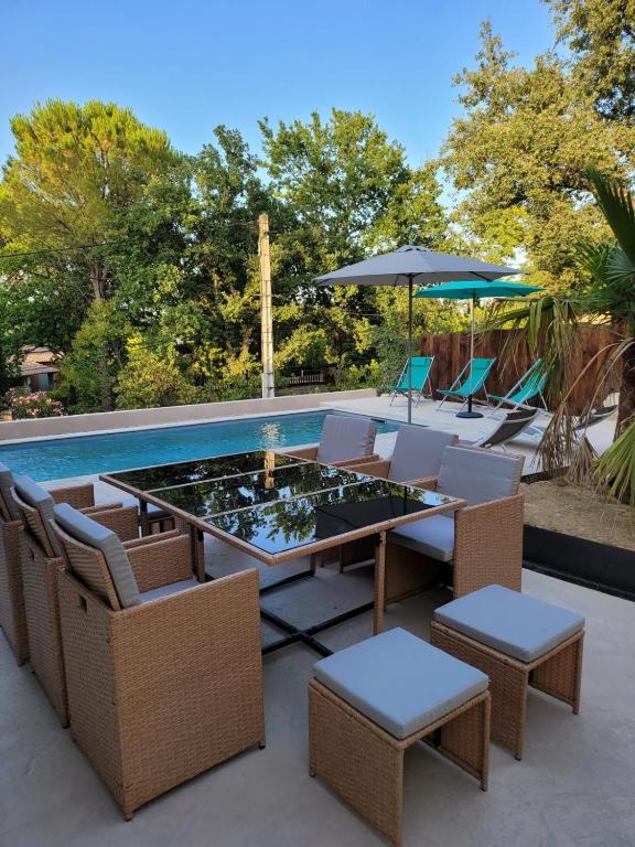 un patio avec une table et des chaises et une piscine dans l'établissement Villa Les Roches du Montélit, à Saint-Paul-Trois-Châteaux
