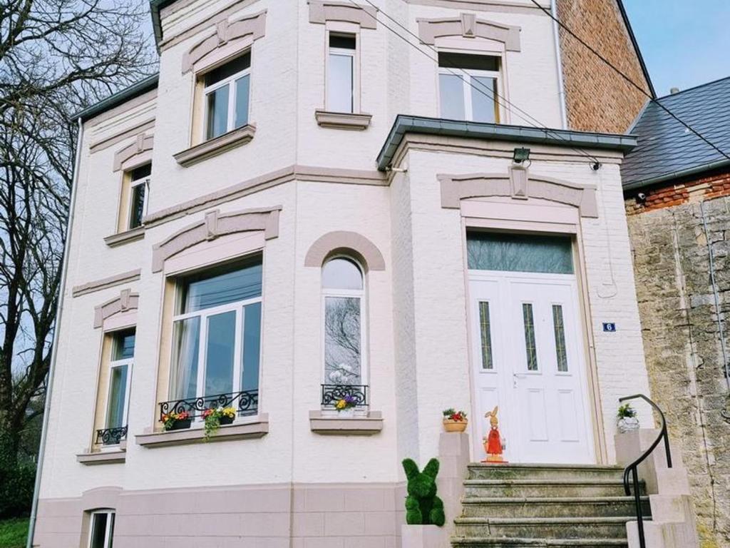 a white house with a cat on the front door at Villa spacieuse avec jardin, terrasse, et équipements complets à Baives, proche Belgique et Val Joly - FR-1-510-218 in Baives