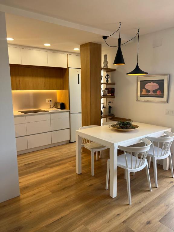 a white kitchen with a white table and chairs at Ancora Apartment in Vilanova i la Geltrú