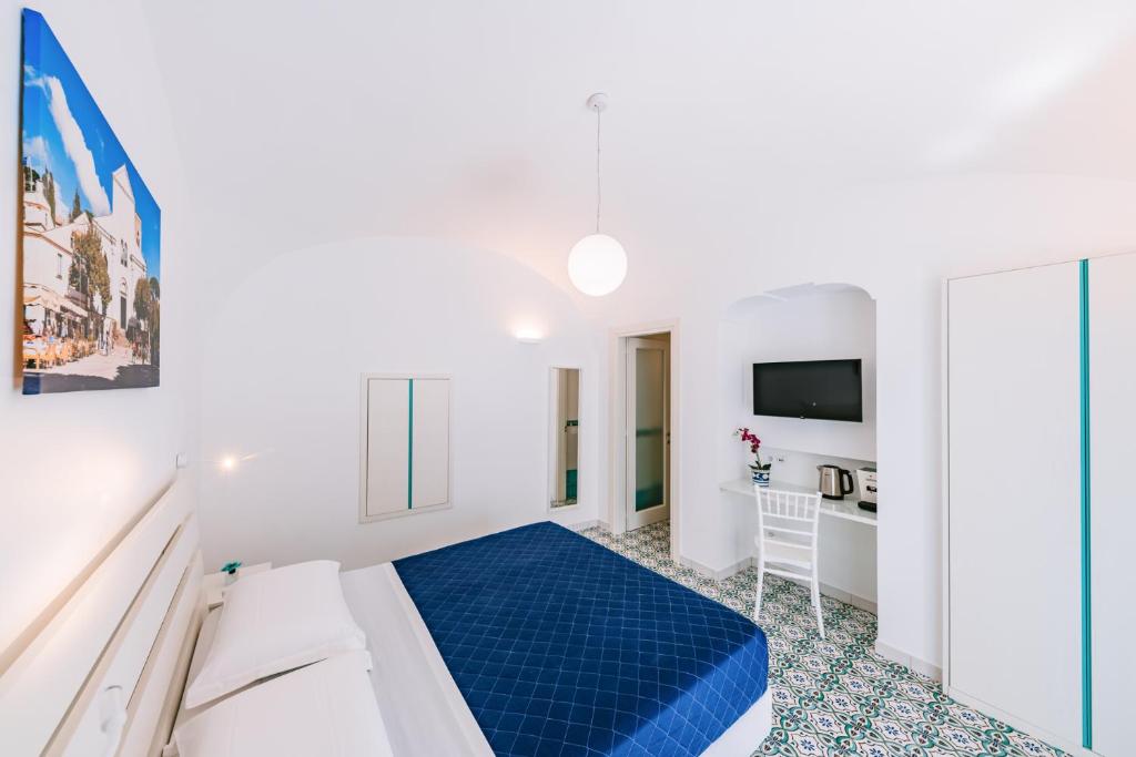 a white bedroom with a blue bed and a desk at Na Stanza in centro in Ravello