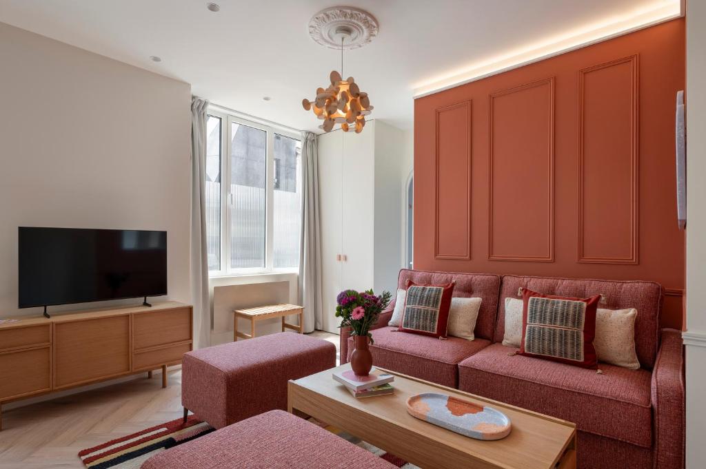 a living room with a red couch and a tv at New Flat Terracotta Style - Greater Paris district in Malakoff