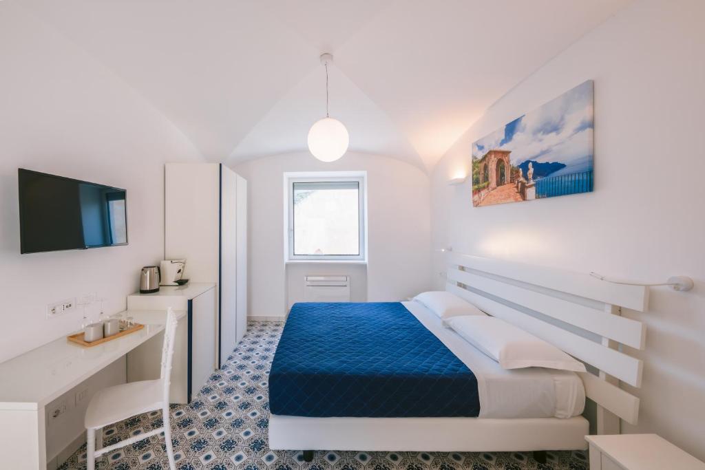 a white bedroom with a bed and a desk at A Gradillo holiday rooms in Ravello