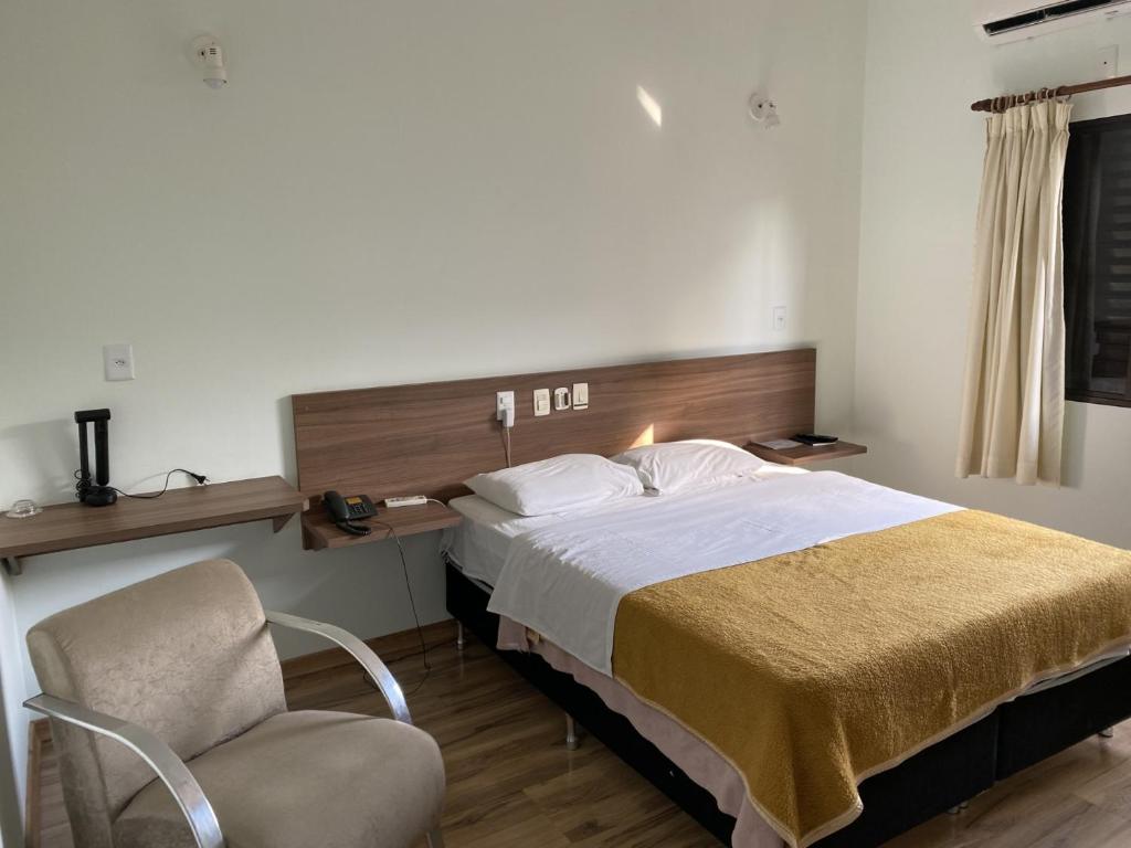 a hotel room with a bed and a chair at Hotel Valle Sul in Registro