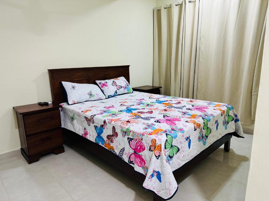 Un dormitorio con una cama con un edredón floral. en Apartamentos swiss, en Sosúa