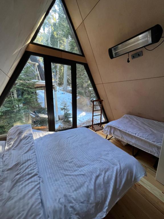una camera da letto con un letto e una grande finestra di Bakhmaro A-frame a Chʼkhakoura