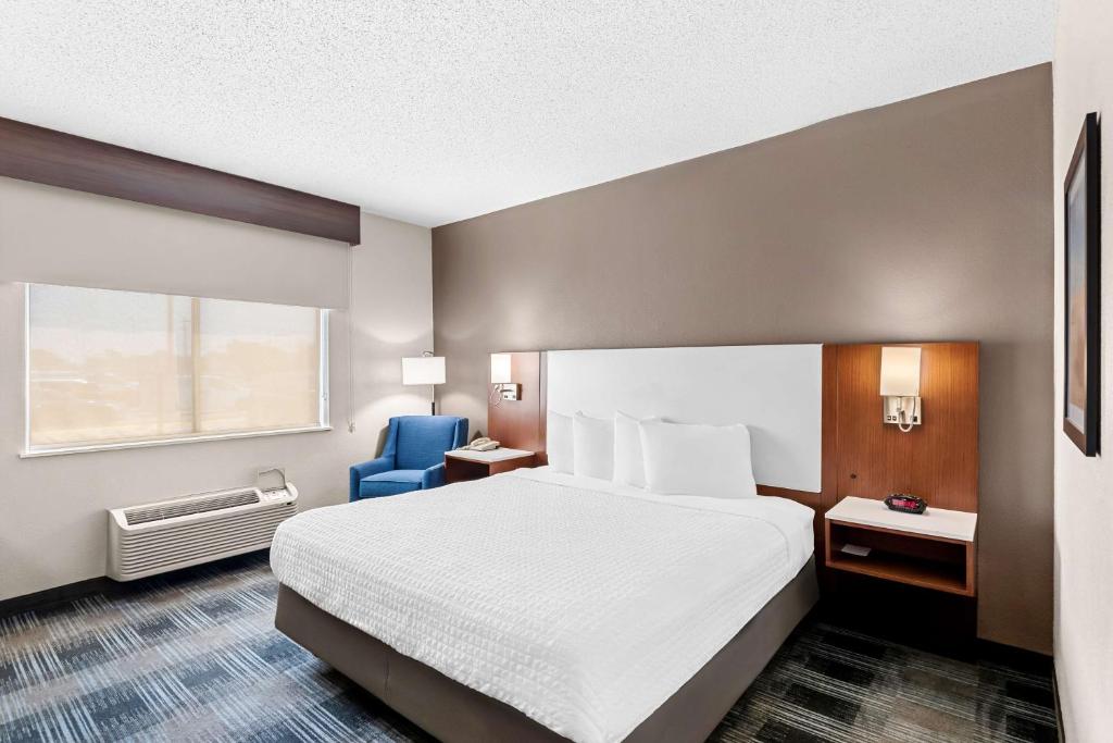 a hotel room with a bed and a blue chair at Best Western Ottumwa Inn & Suites in Ottumwa