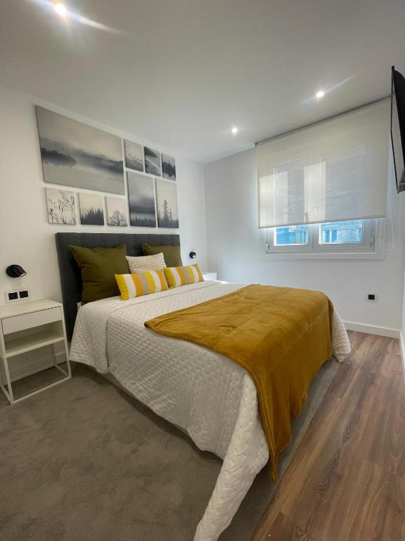 - une chambre blanche avec un grand lit et des oreillers jaunes dans l'établissement Villa Valentina Cíes, à Vilagarcía de Arousa