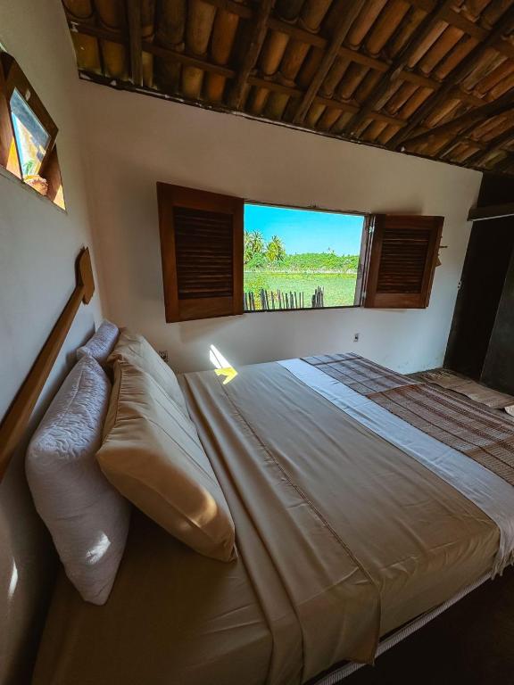a bedroom with a large bed with a large window at Refúgio CAJUÍ in Barreirinhas