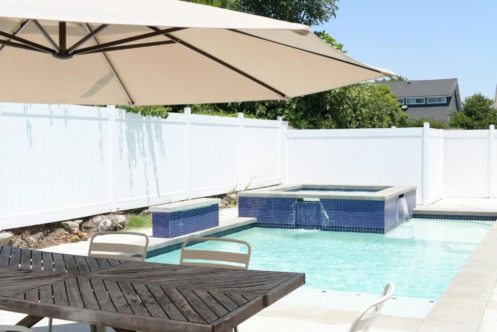 einen Pool mit Sonnenschirm, Tisch und Stühlen in der Unterkunft Lux 6BedRoom Villa with Salted Pool, Hot tub and near Disneyland in Anaheim