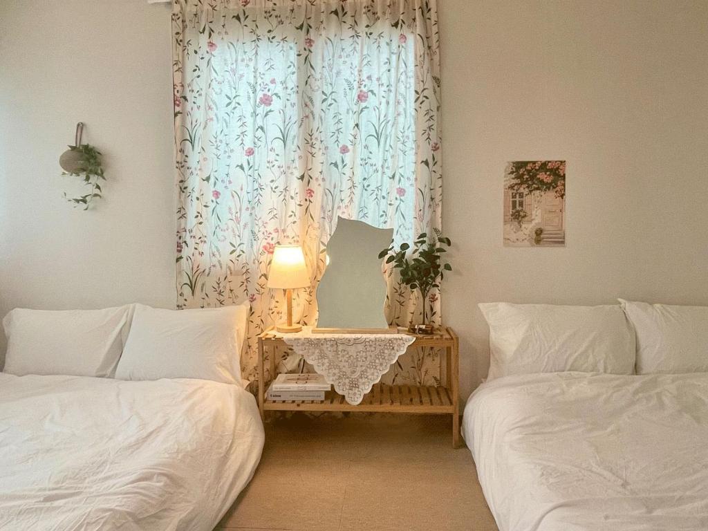 a bedroom with two beds and a table with a lamp at sentimental in Busan
