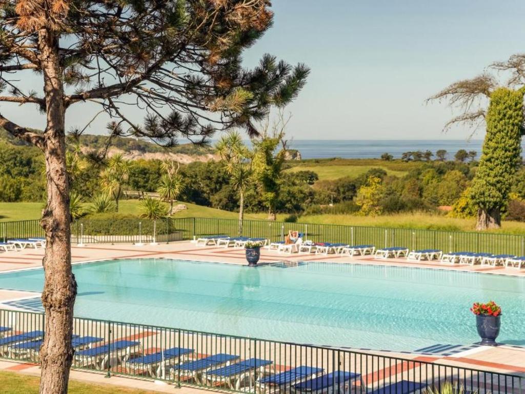 una gran piscina con sillas y un árbol en T2 avec piscine sur la Corniche - FR-1-239-1084, en Urrugne