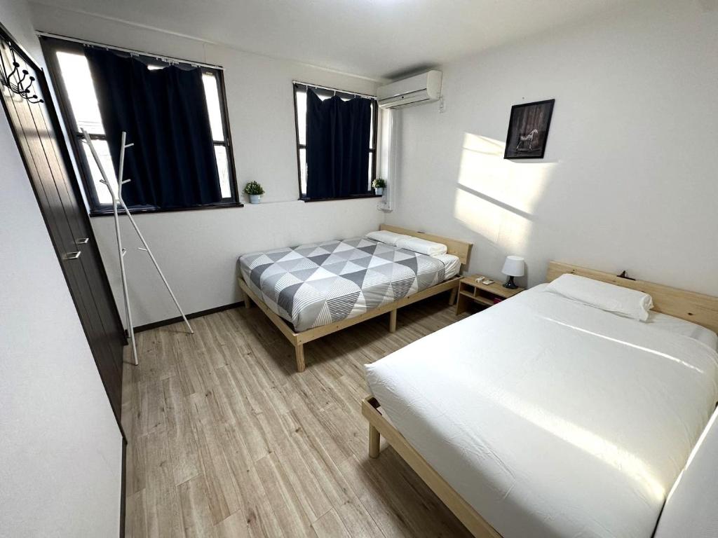 a small room with two beds and a window at GEGE house 201室 in Osaka