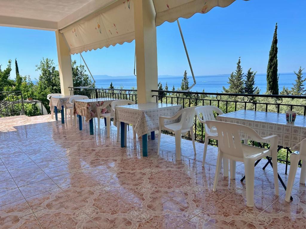 a row of tables and white chairs on a balcony at Vila 23 in Dhërmi