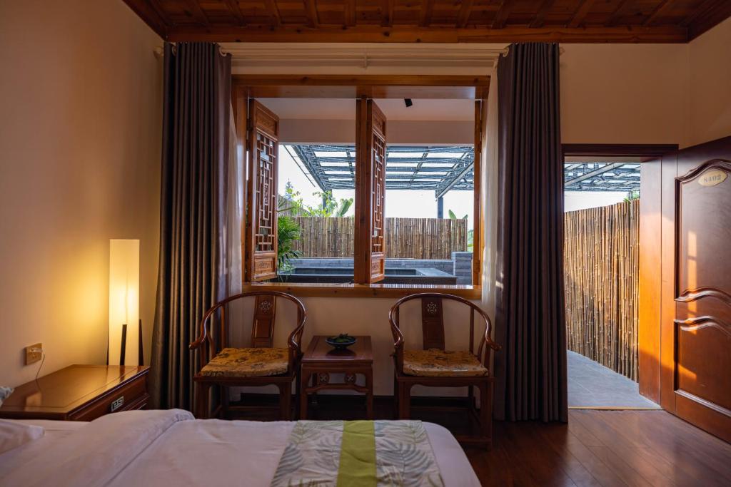 a bedroom with a bed and two chairs and a window at 青城山泉青小院温泉中式民宿 in Taiping