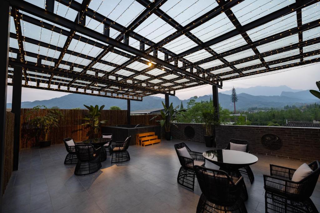a patio with tables and chairs and a glass roof at 青城山泉青小院温泉中式民宿 in Taiping