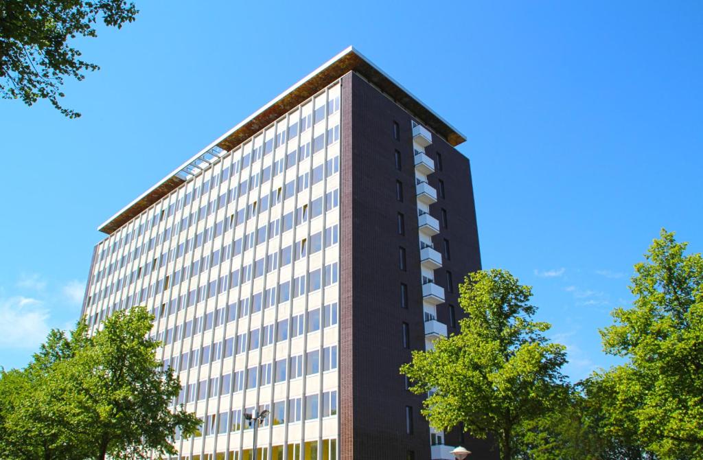 a tall black building with trees in front of it at Dutchies Hostel in Amsterdam