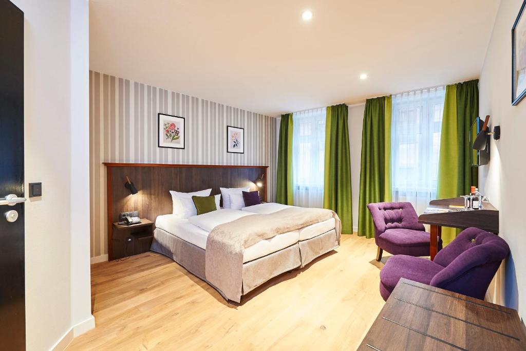 a hotel room with a bed and two purple chairs at Hotel Hauser Boutique in Nürnberg