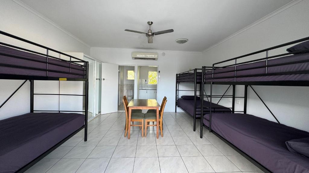 Zimmer mit 2 Etagenbetten sowie einem Tisch und Stühlen in der Unterkunft Accom KC's in Airlie Beach