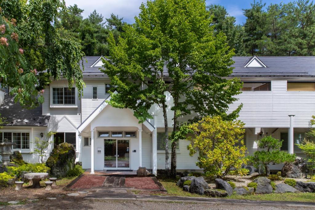 uma casa branca com uma árvore no jardim da frente em Fujiyama Inn Conifer em Fujiyoshida