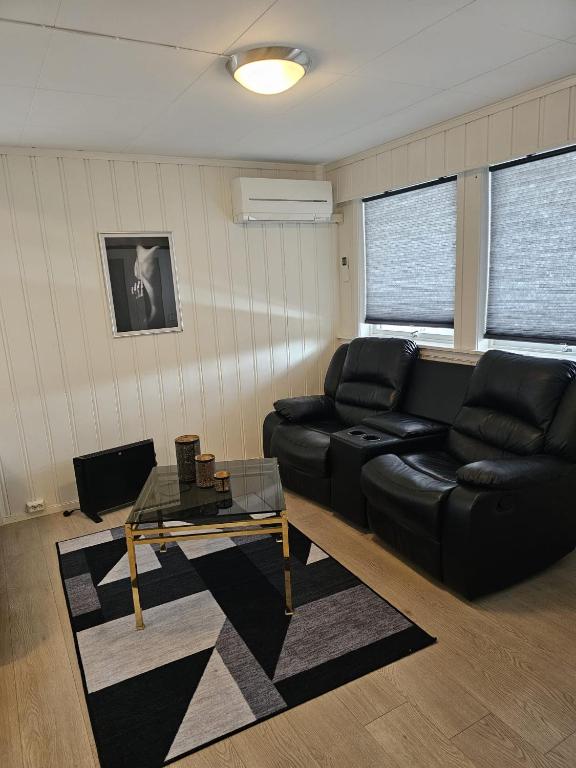 a living room with a black leather couch and a table at Rooms with free parking in Lillestrøm