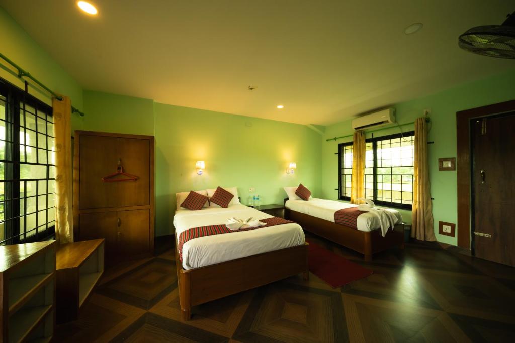 a hotel room with two beds and green walls at Wild Adventure Resort - Sunset Point in Sauraha