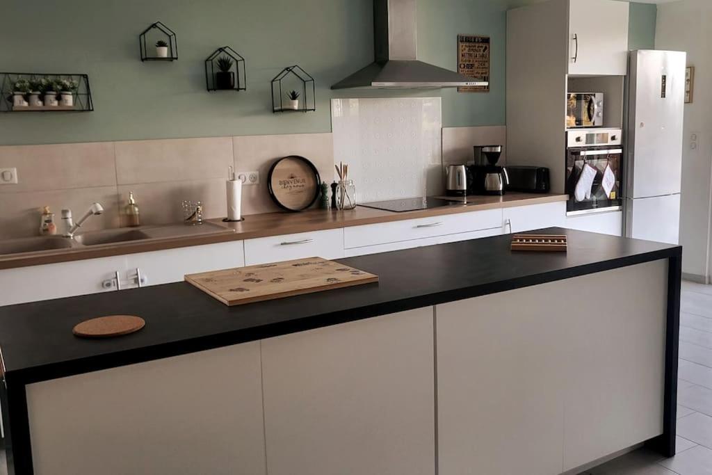 a kitchen with white cabinets and a black counter top at Au cœur de la nature Le cerf in Saint-Vincent-Jalmoutiers