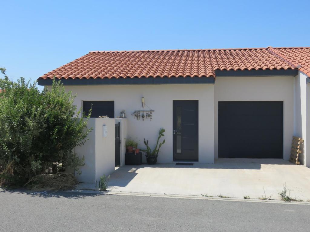une maison blanche avec un toit rouge et deux portes de garage dans l'établissement L'hibiscus, à Narbonne