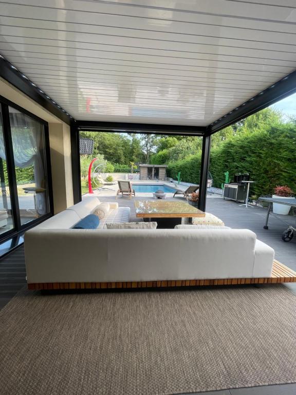 un salon avec un grand canapé blanc sur un patio dans l'établissement Villa avec piscine 35 min de Paris, à Étiolles