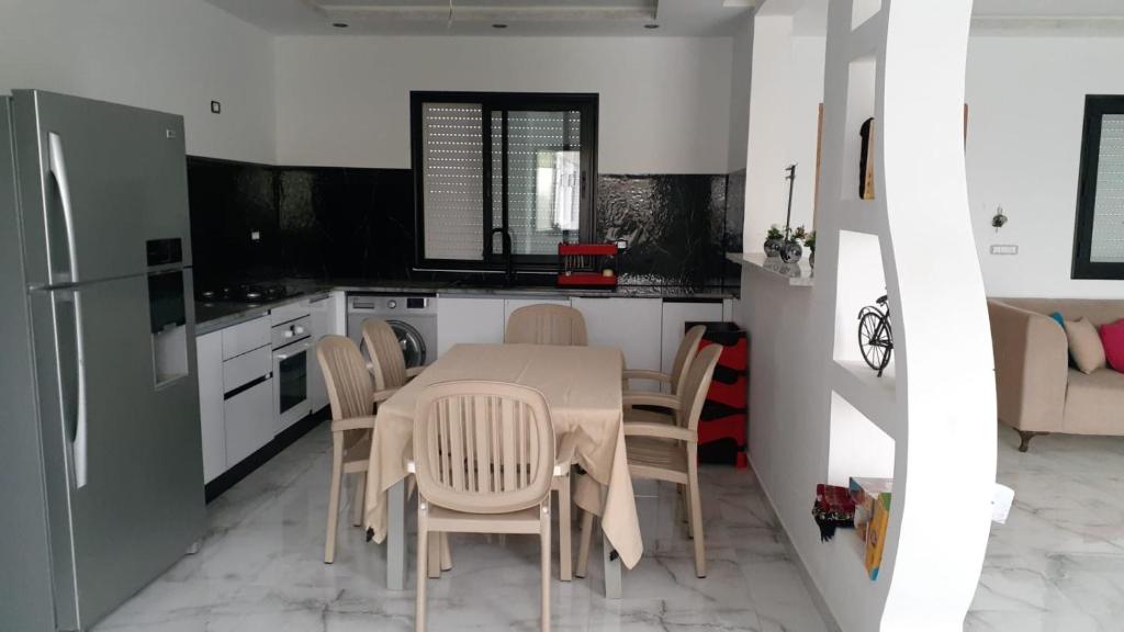 een keuken met een tafel, stoelen en een koelkast bij Villa Kenza in Douar el Khima
