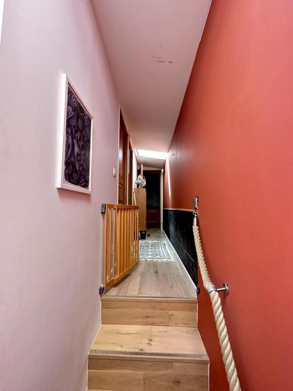 un couloir avec des murs orange et des escaliers en bois dans l'établissement Maison de campagne à Paris, à Montreuil
