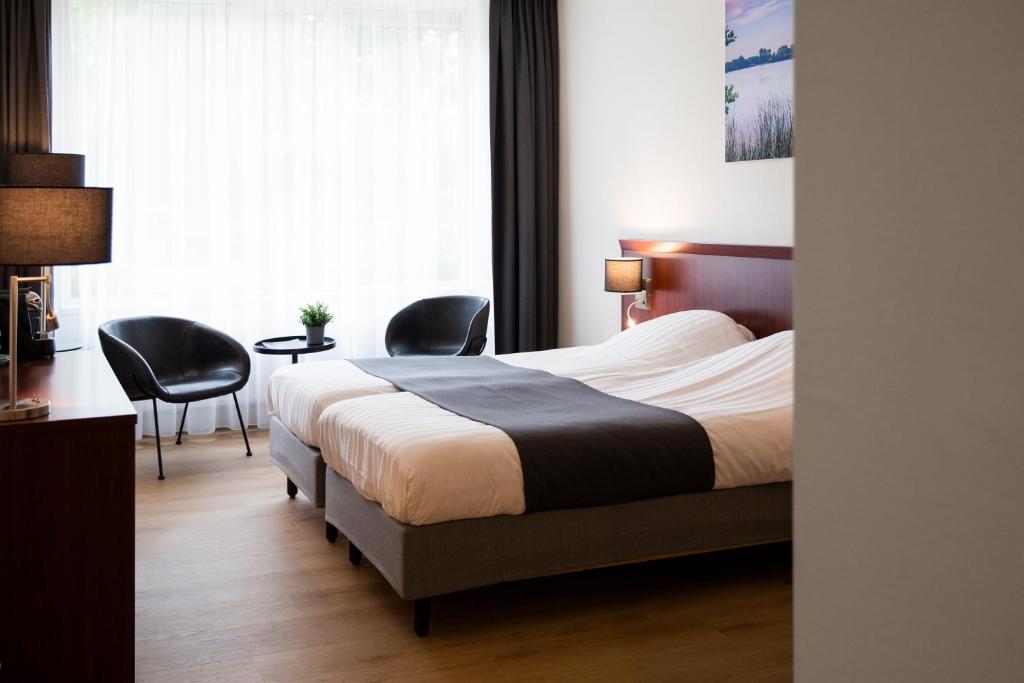 a hotel room with a bed and two chairs at Hotel Umberto in Wijchen