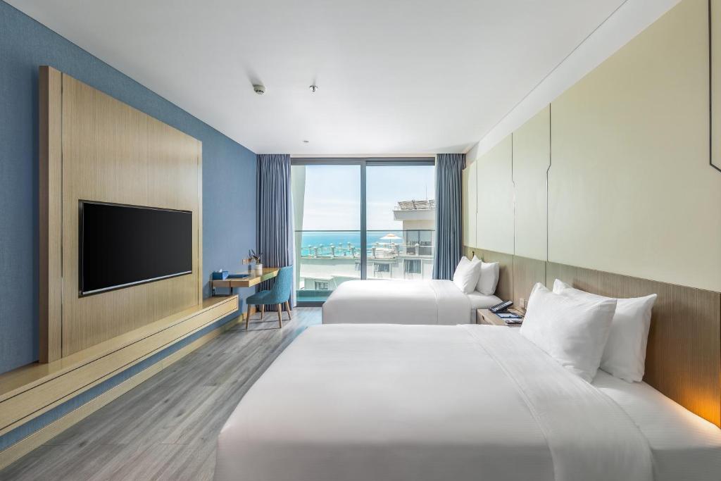 a hotel room with two beds and a flat screen tv at Awaken Da Nang Hotel in Danang