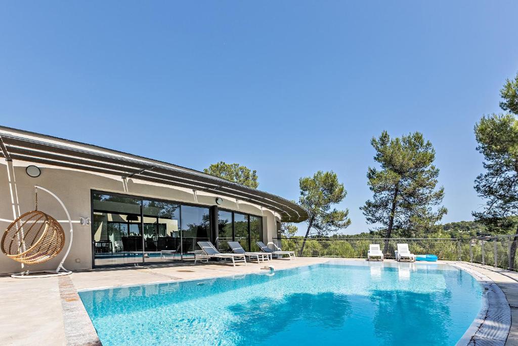 une piscine avec des chaises et une maison dans l'établissement Superbe et spacieuse propriété avec piscine et spa, à Saint-Gély-du-Fesc