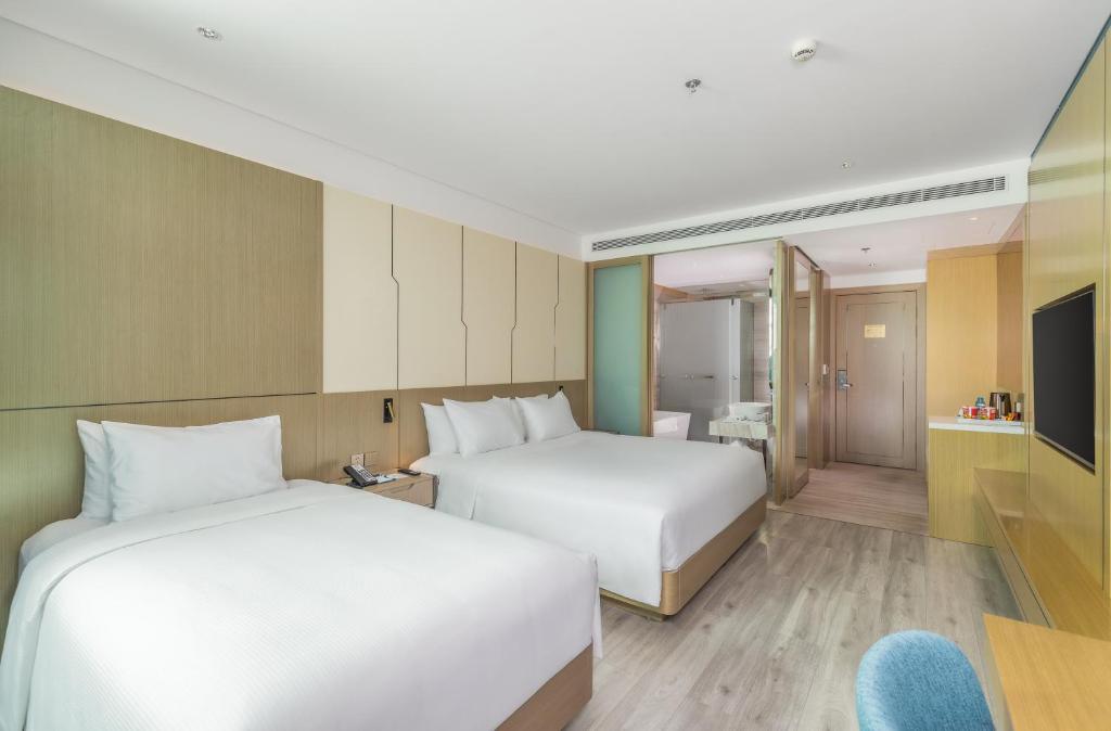 A spacious twin room with two beds, built-in storage, television and a small seating area.