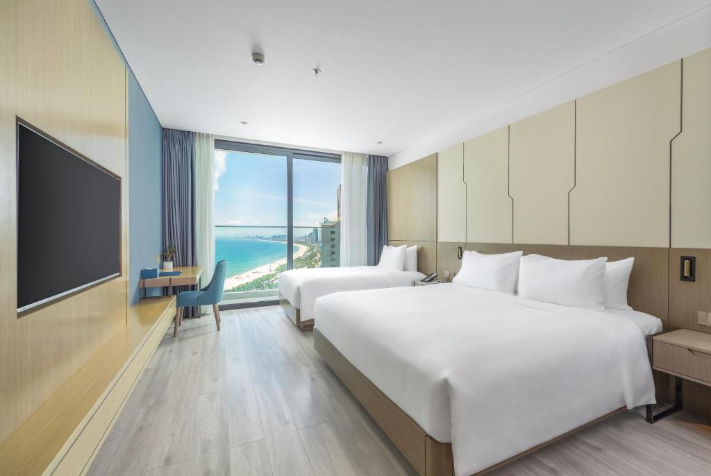 a hotel room with two beds and a television at Awaken Da Nang Hotel in Danang