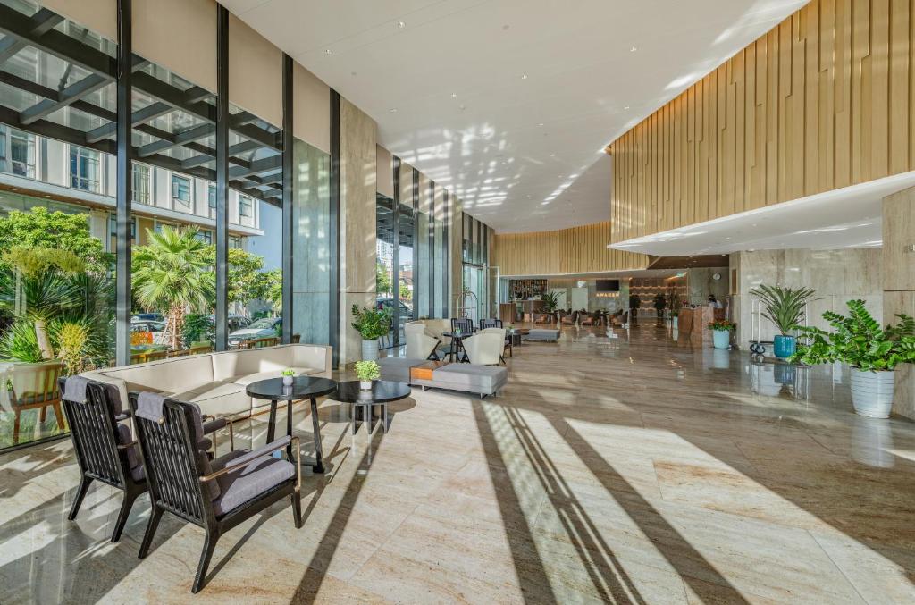 an office lobby with tables and chairs and windows at Awaken Da Nang Hotel in Danang