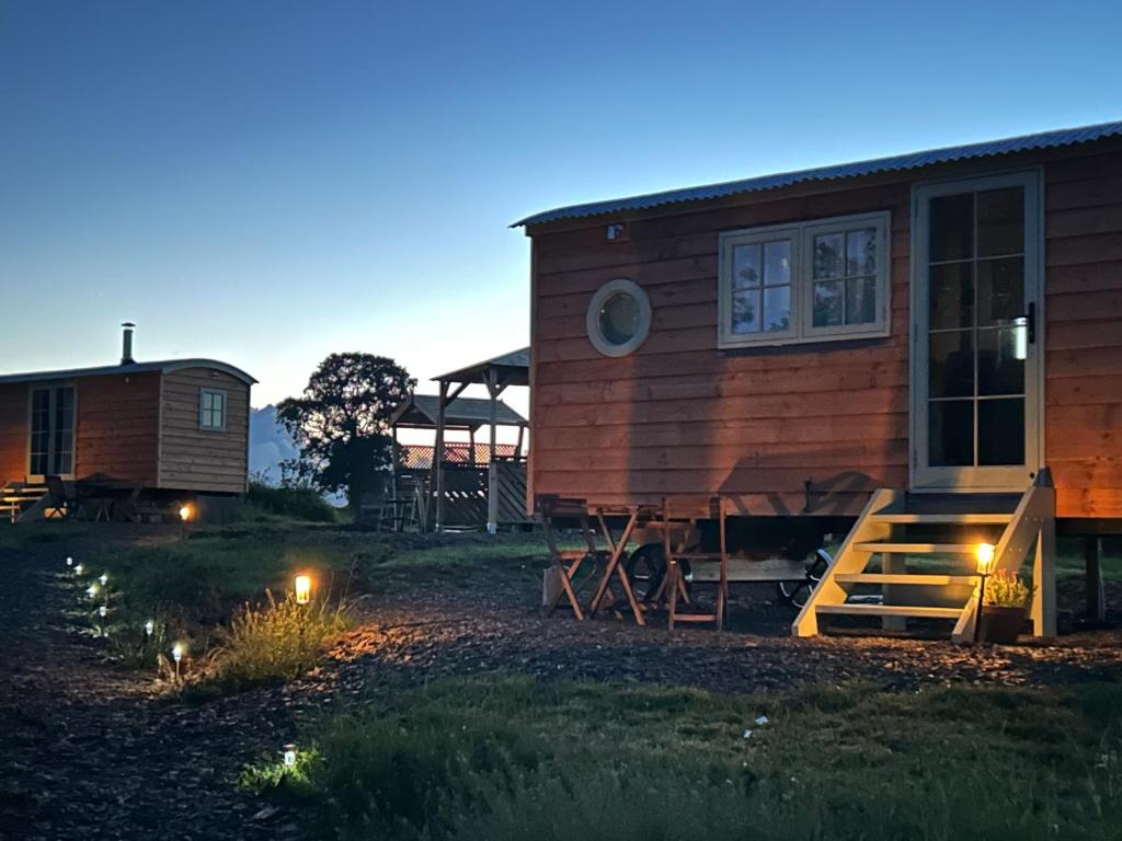 a home with a porch and a house with lights at Charming shepherds hut with hottub in Umberleigh Bridge