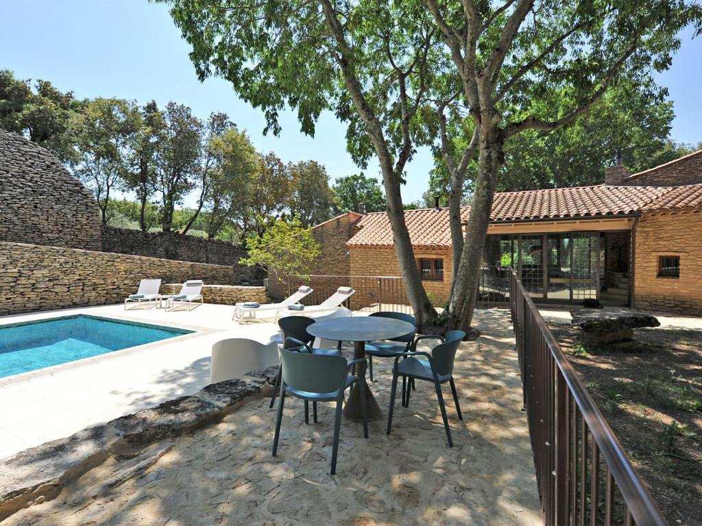un patio avec une table et des chaises à côté d'une piscine dans l'établissement Le Chant des Bories, à Gordes