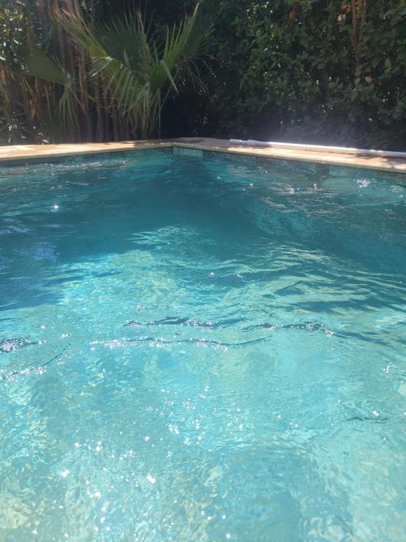 une grande piscine d'eau bleue dans une cour dans l'établissement Villas près de la plage, à Six-Fours-les-Plages