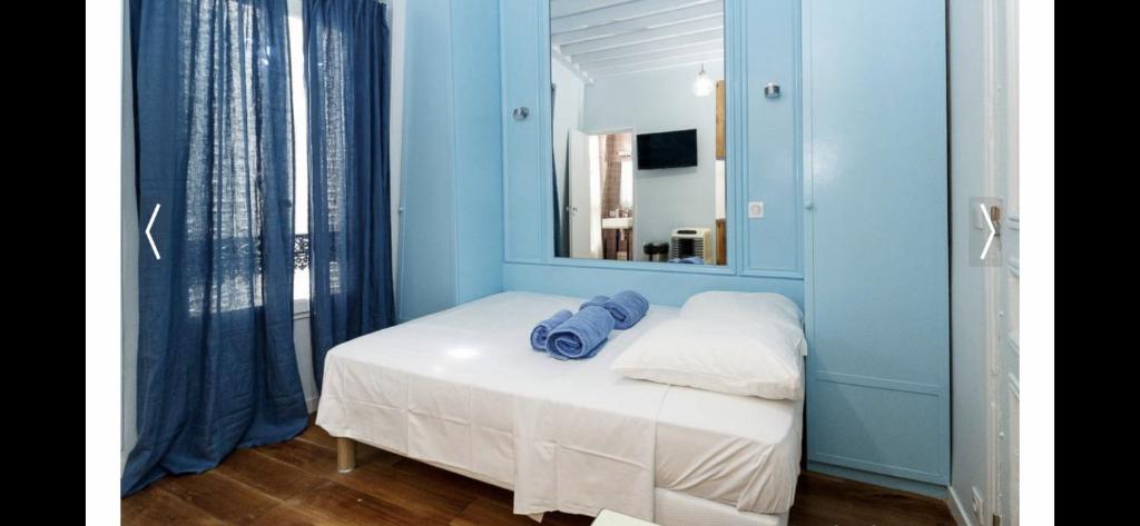 - une chambre avec des murs bleus et un lit avec un miroir dans l'établissement PARIS 4 Le Marais Place des Vosges, à Paris