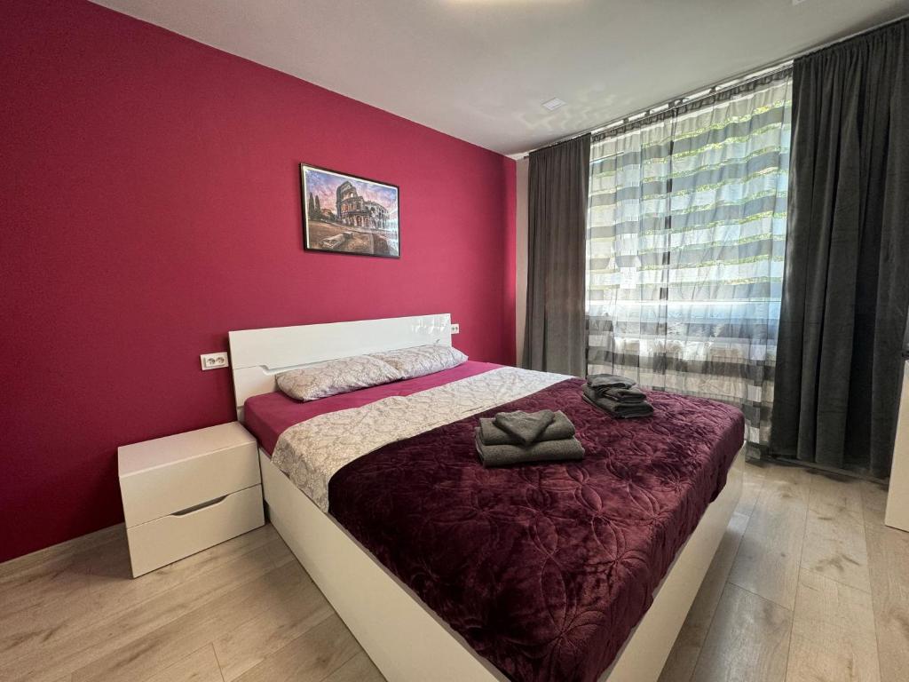 a bedroom with a bed with a red wall at West Park Apartment in Sofia