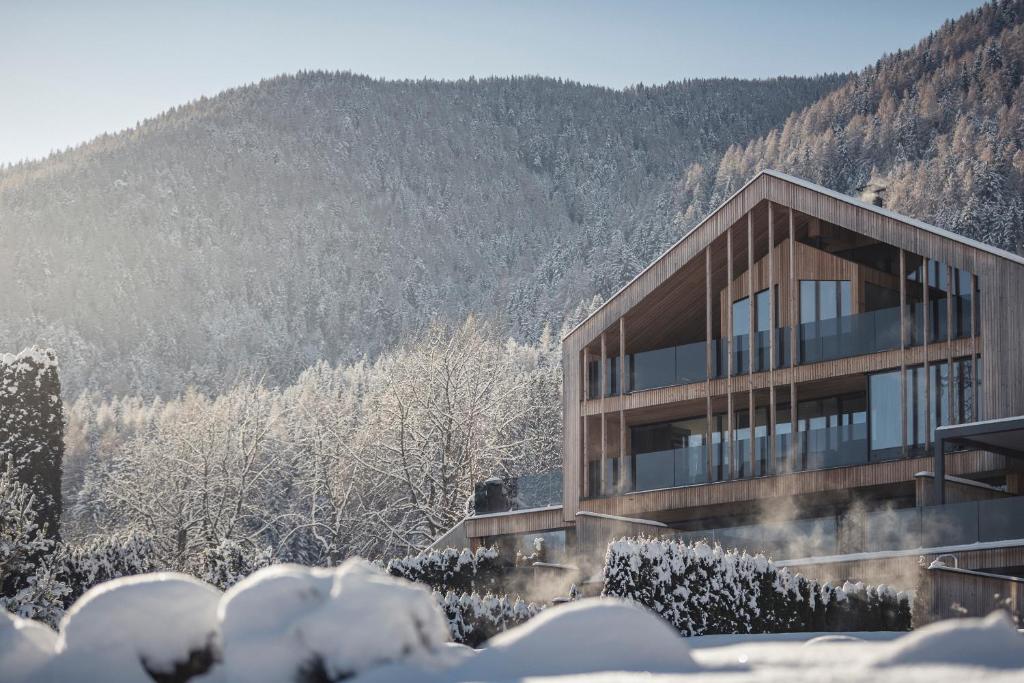 ein Gebäude im Schnee mit einem Berg im Hintergrund in der Unterkunft Chalet PURMONTES in St. Lorenzen