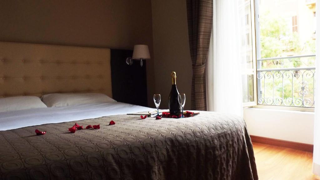 un letto con una bottiglia di vino e bicchieri sopra di Hotel Nautilus a Roma