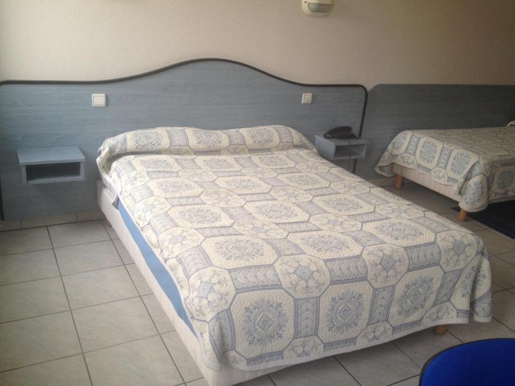 a bedroom with a bed with a quilt on it at Hotel Le Strasbourg in Mulhouse